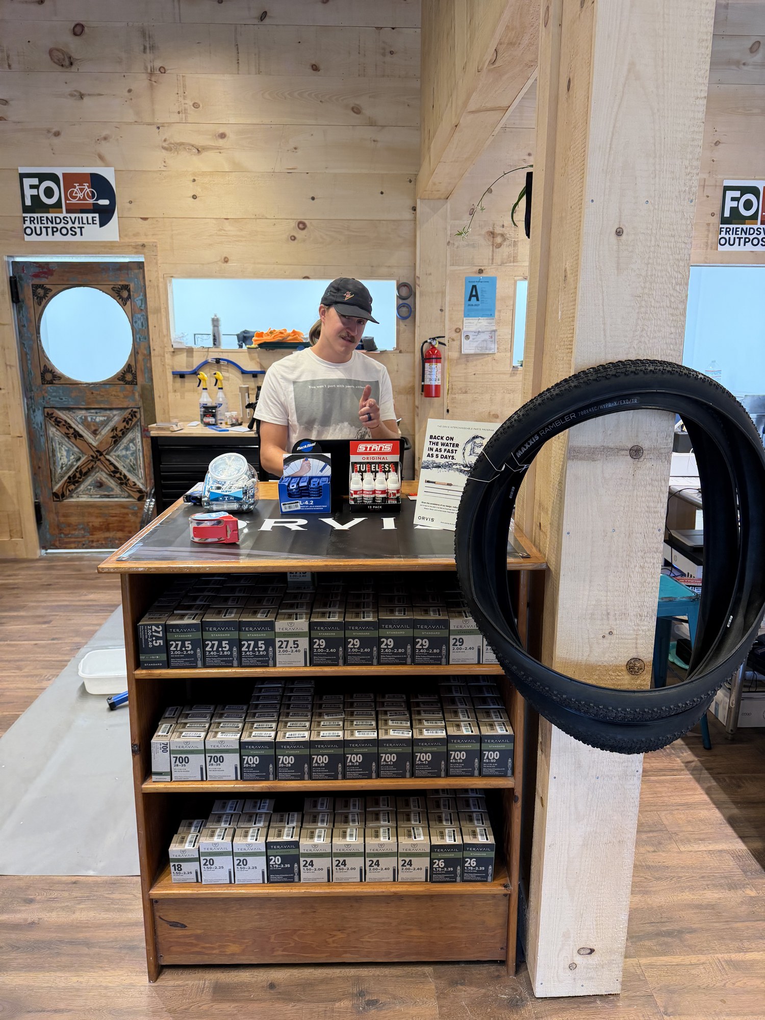 Inside Friendsville Outpost, with bike tires, tubes, and service supplies at the counter.